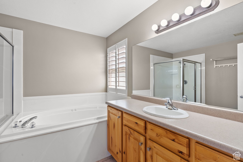 Bathroom with a stall shower, a bath, and vanity