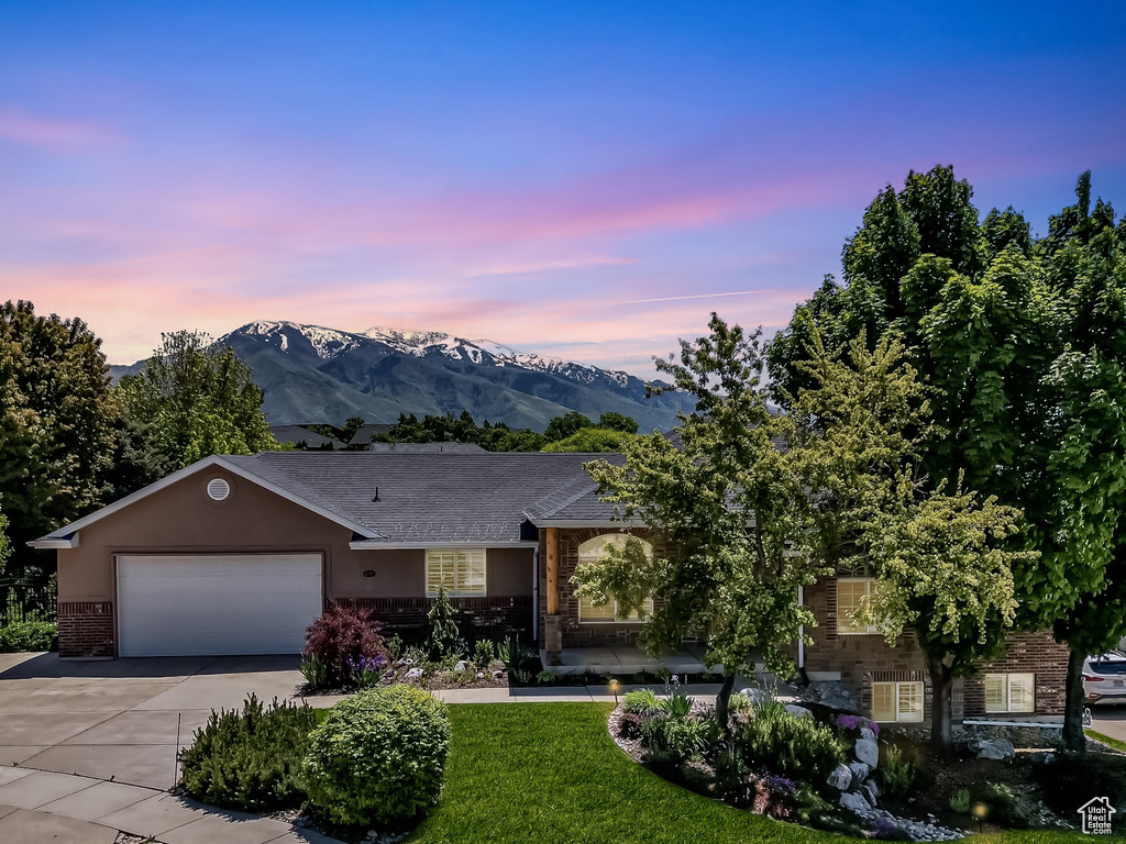 View of front of house featuring brick siding, concrete driveway, an attached garage, a mountain view, and stone siding