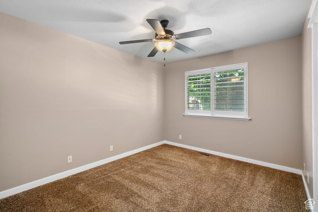 Unfurnished room with carpet floors, ceiling fan, and baseboards