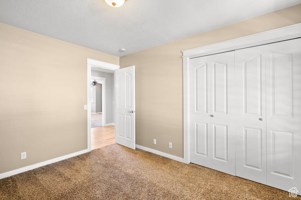 Unfurnished bedroom featuring carpet, baseboards, and a closet