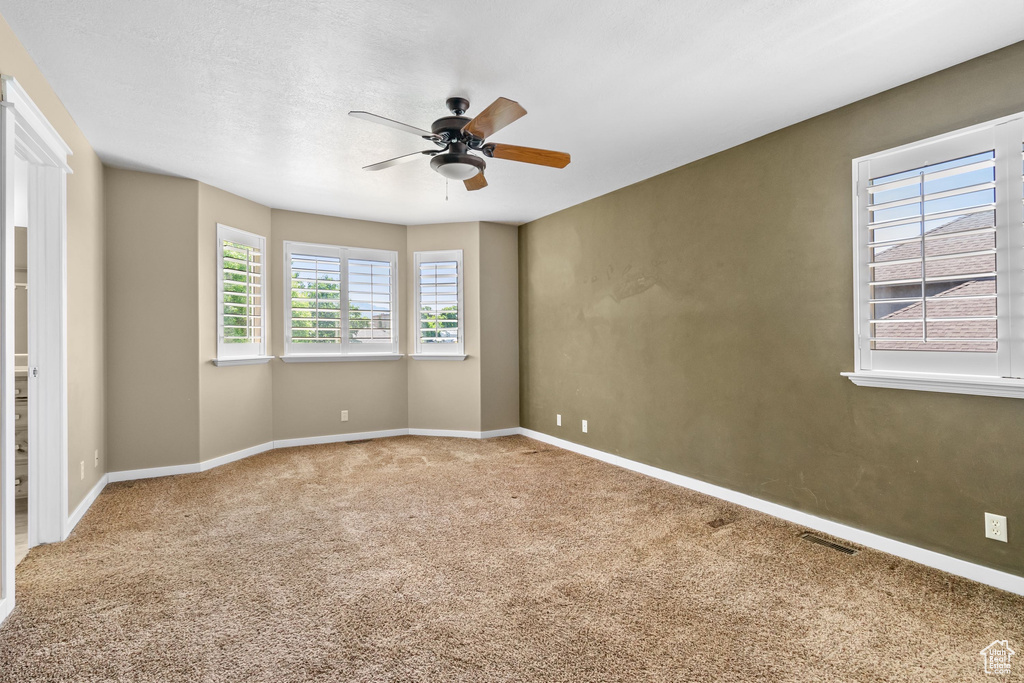 Carpeted empty room featuring ceiling fan and baseboards