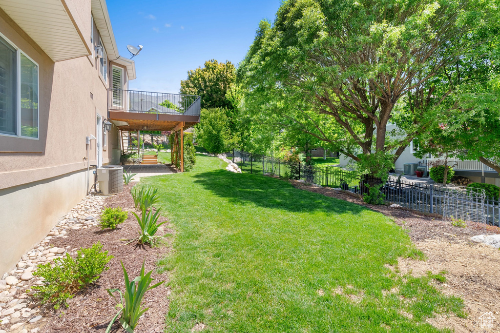 View of yard featuring central AC unit and a balcony