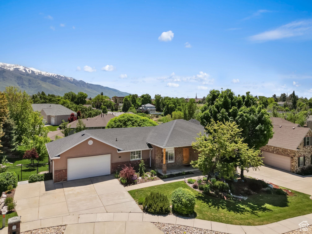 Ranch-style home with driveway, an attached garage, brick siding, a mountain view, and stone siding