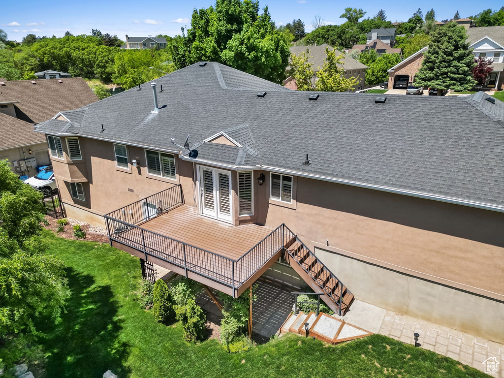 Rear view of property featuring a shingled roof, stucco siding, a wooden deck, and stairway