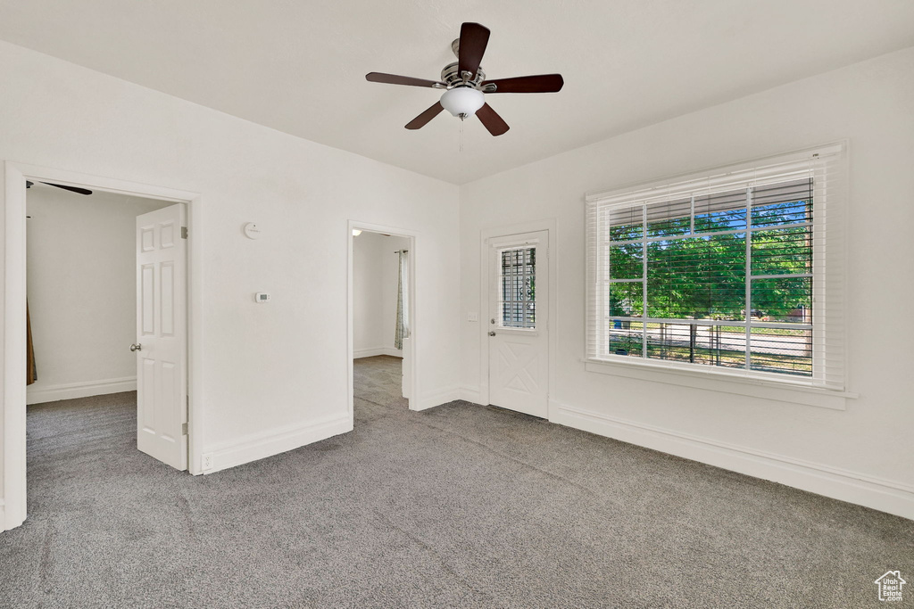 Carpeted empty room featuring ceiling fan and baseboards