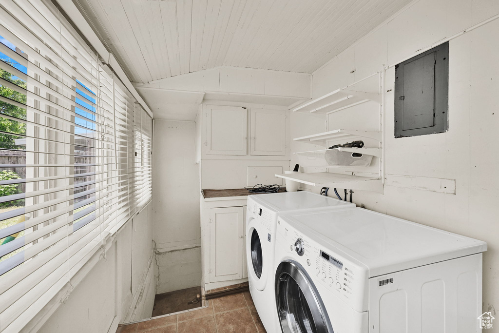Washroom featuring electric panel, independent washer and dryer, light tile patterned flooring, and cabinet space