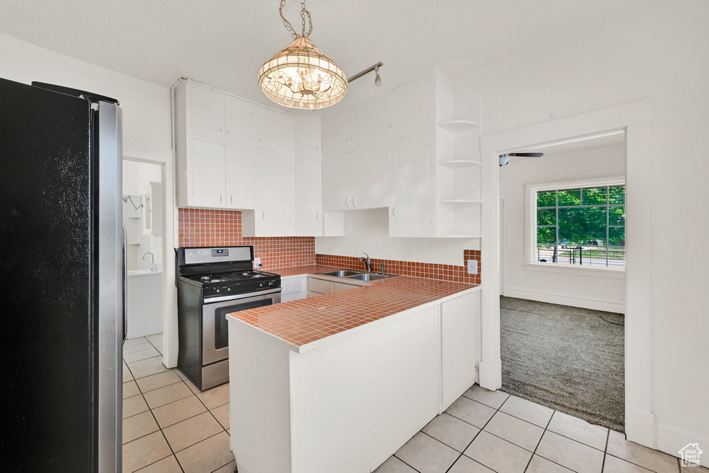 Kitchen featuring stainless steel appliances, a sink, white cabinetry, light tile patterned floors, and a peninsula