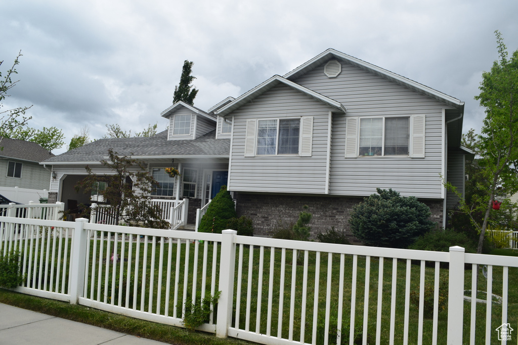 Tri-level home featuring a porch, brick siding, and a garage