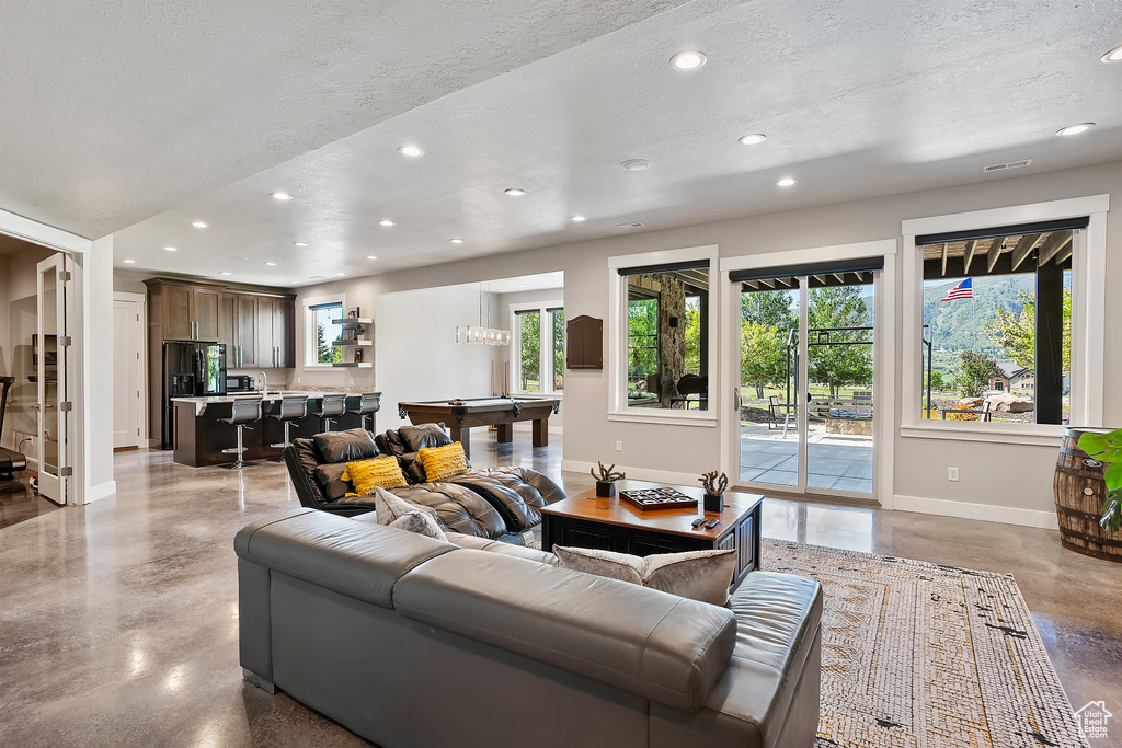 Living area featuring recessed lighting, billiards table, baseboards, concrete flooring, and healthy amount of natural light