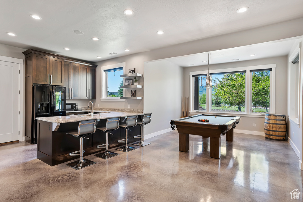 Rec room with finished concrete floors, baseboards, healthy amount of natural light, and recessed lighting