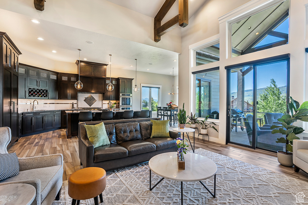 Living room with light wood-style flooring, a towering ceiling, and recessed lighting