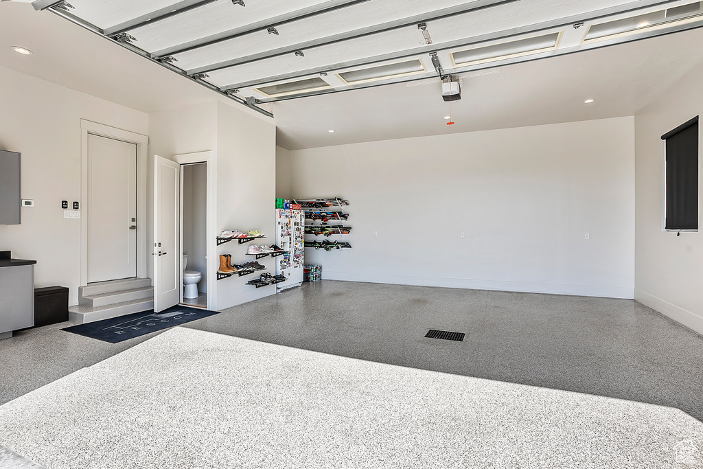 Garage featuring a garage door opener, baseboards, and recessed lighting
