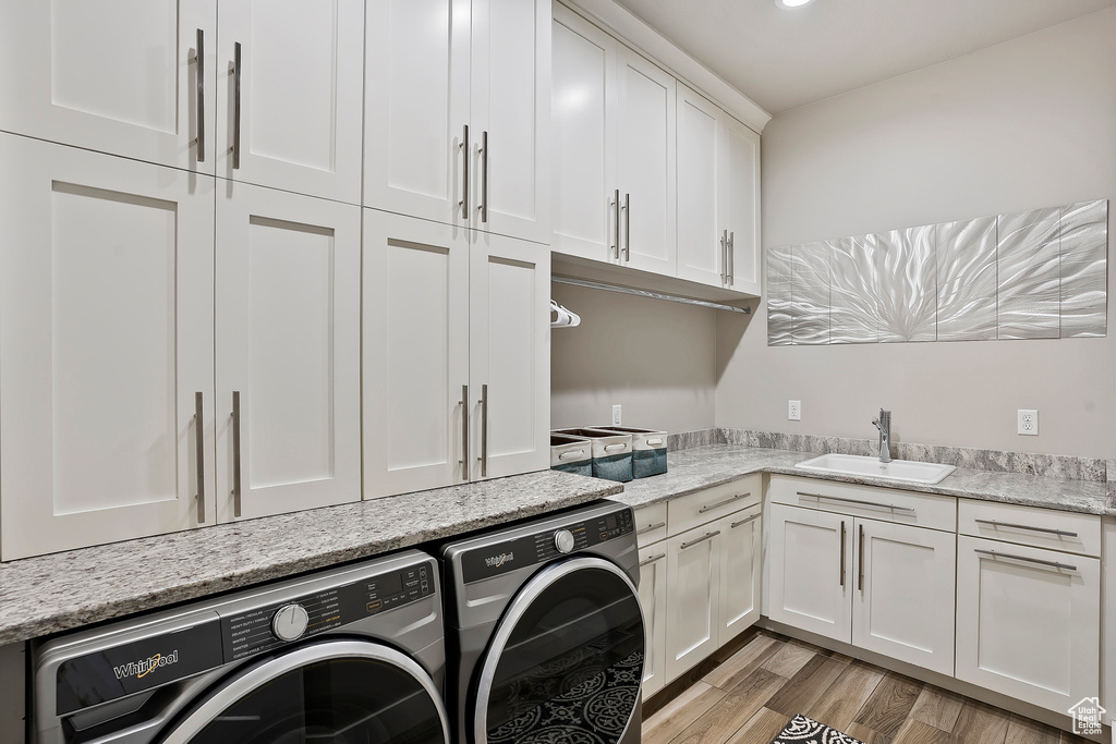 Washroom with washer and clothes dryer, cabinet space, and light wood finished floors