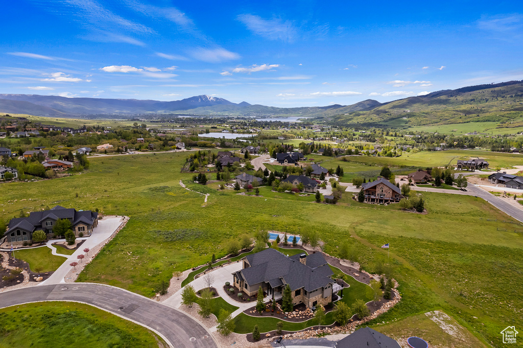 Aerial view of property and surrounding area featuring mountains and nearby suburban area