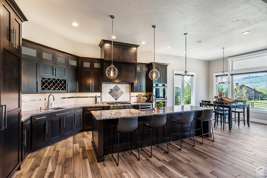 Kitchen featuring a sink, light wood finished floors, tasteful backsplash, recessed lighting, and a textured ceiling
