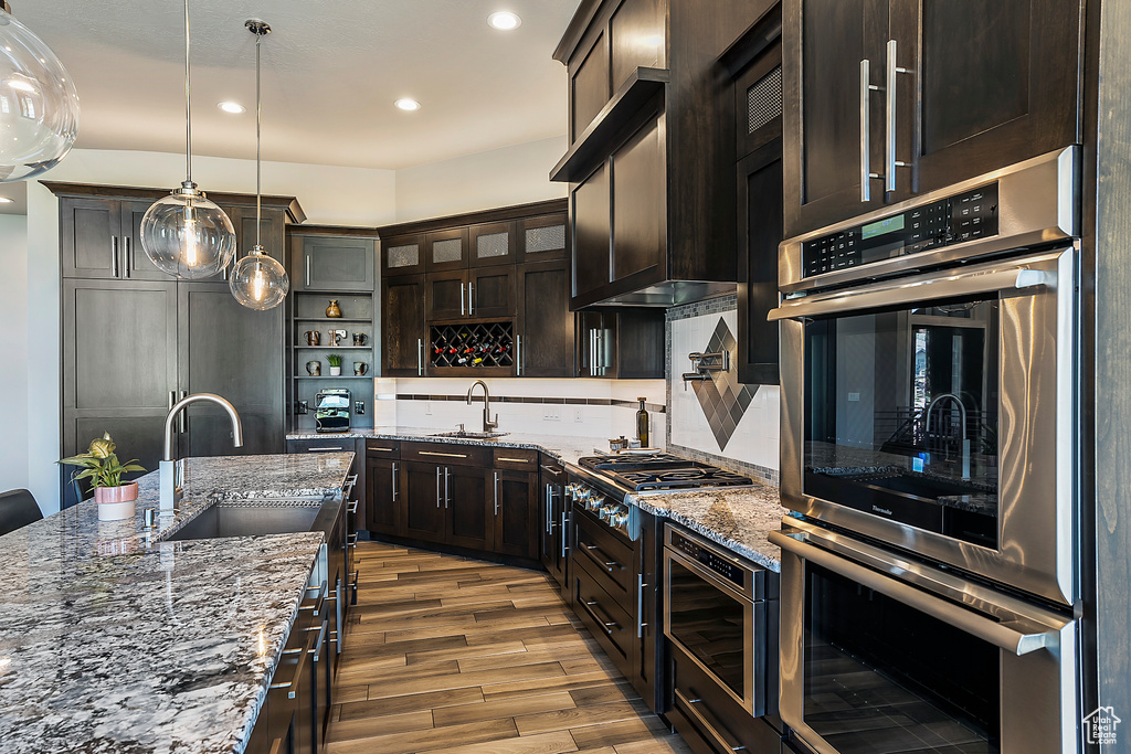 Kitchen with open shelves, stainless steel appliances, a sink, wood finished floors, and recessed lighting
