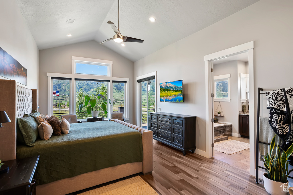 Bedroom featuring wood finished floors, high vaulted ceiling, ensuite bathroom, access to exterior, and a ceiling fan