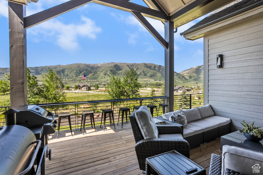 Wooden terrace featuring a mountain view, an outdoor living space, and a grill