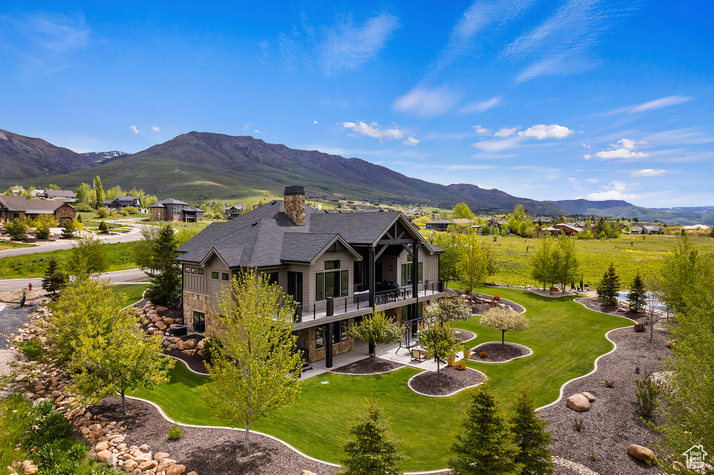 Rear view of property with a patio, a lawn, a chimney, a mountain view, and a balcony