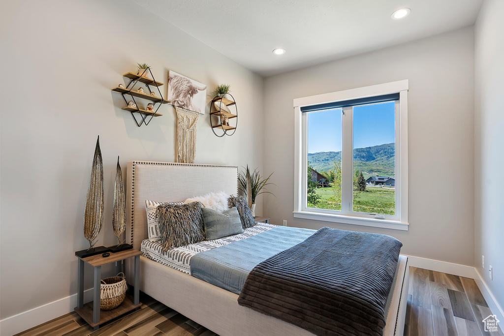 Bedroom with baseboards, wood finished floors, recessed lighting, and a mountain view