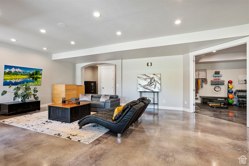 Living room with concrete flooring, baseboards, arched walkways, and recessed lighting