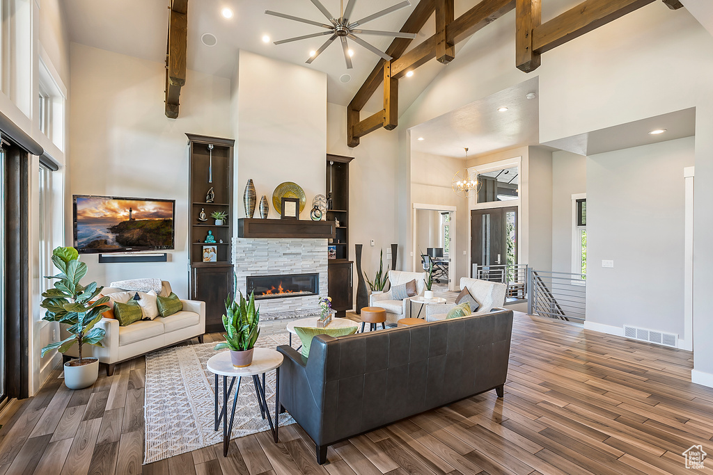 Living area featuring high vaulted ceiling, a fireplace, wood finished floors, baseboards, and beamed ceiling