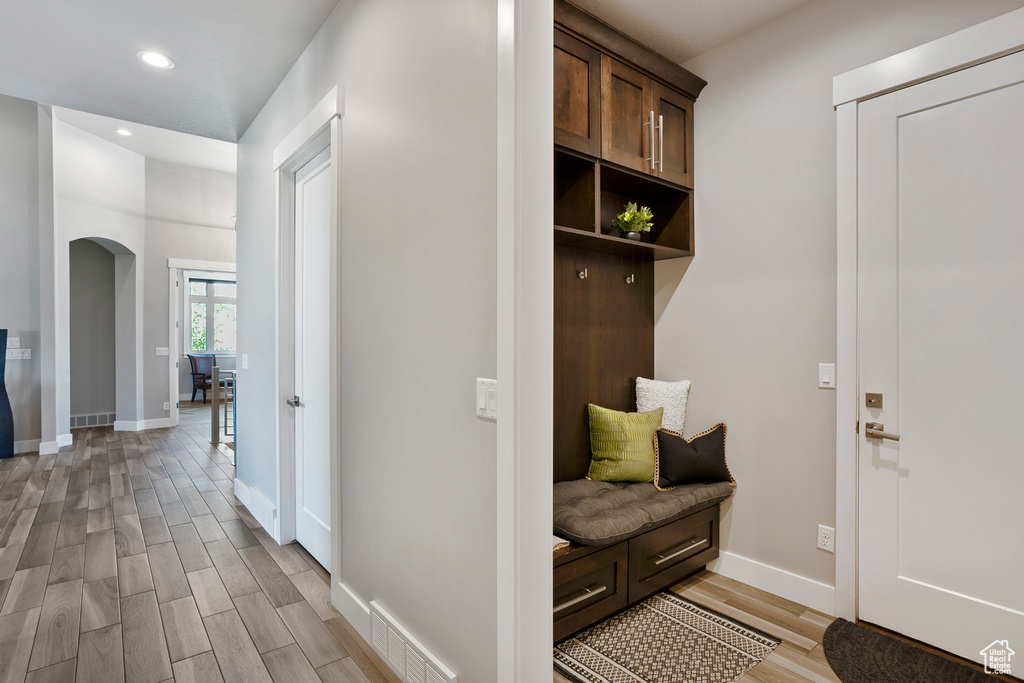 Mudroom with arched walkways, light wood-style flooring, recessed lighting, and baseboards
