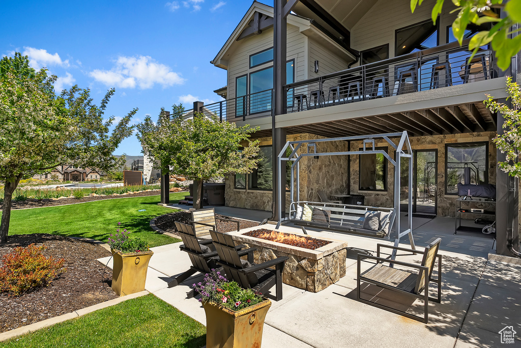 View of patio with an outdoor fire pit and a balcony