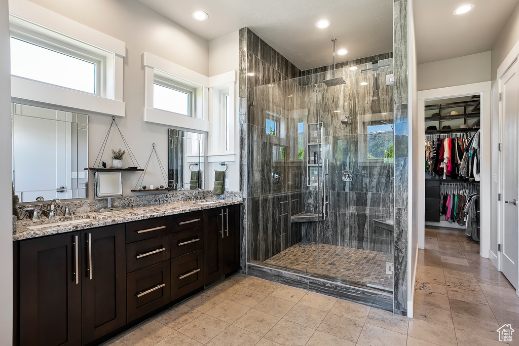 Bathroom with a stall shower, double vanity, recessed lighting, and a walk in closet