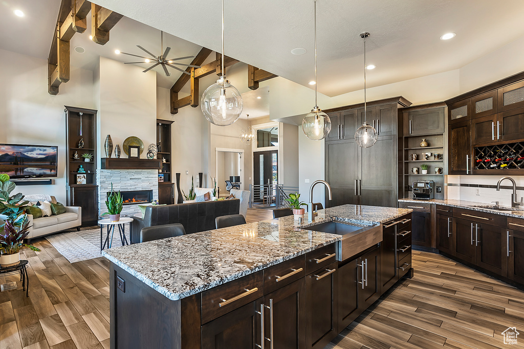 Kitchen with a sink, dark wood-type flooring, an island with sink, high vaulted ceiling, and hanging light fixtures