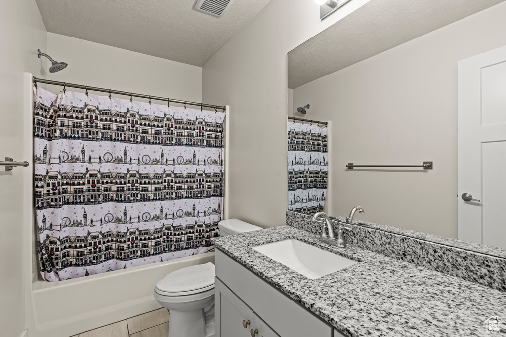 Bathroom featuring toilet, vanity, shower / tub combo, and tile patterned flooring