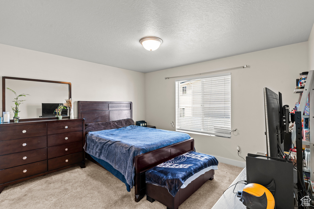 Bedroom with light carpet, a textured ceiling, and baseboards