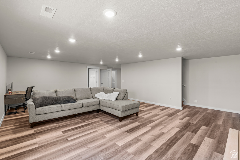 Living area with recessed lighting, light wood finished floors, a textured ceiling, and baseboards