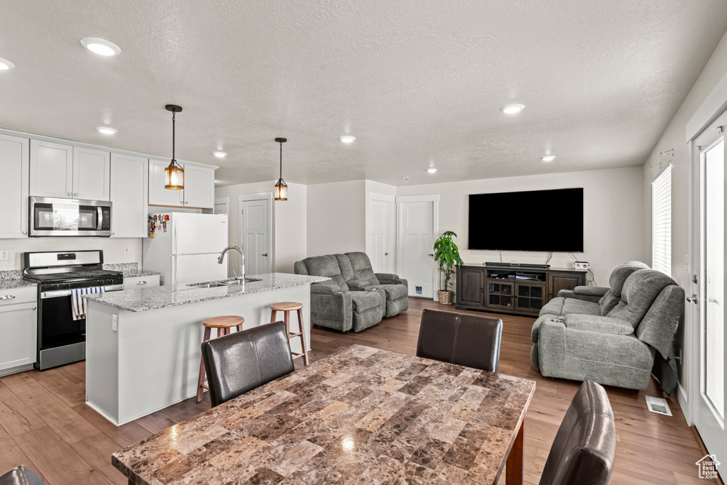 Living area with light wood-style floors, a textured ceiling, and recessed lighting