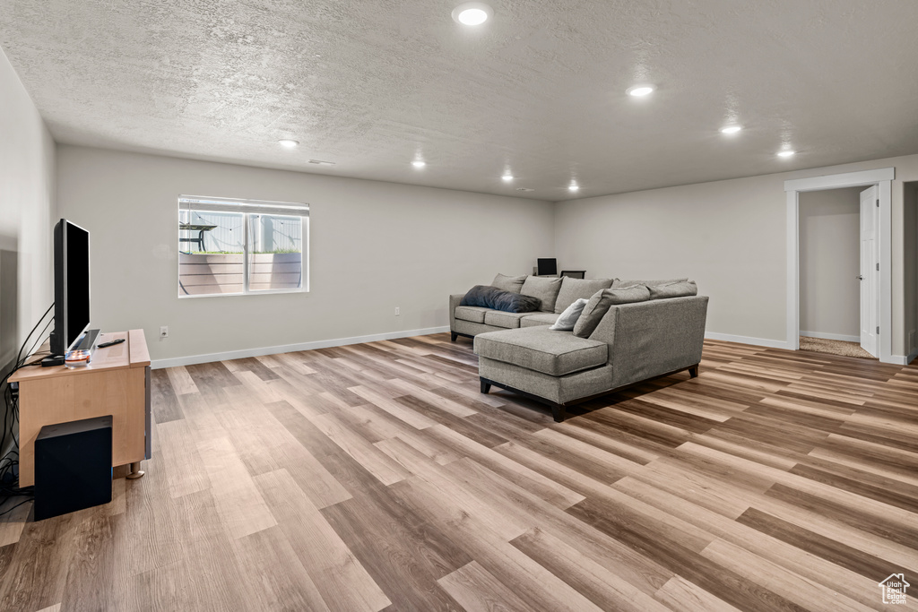 Living area featuring light wood-type flooring, baseboards, recessed lighting, and a textured ceiling