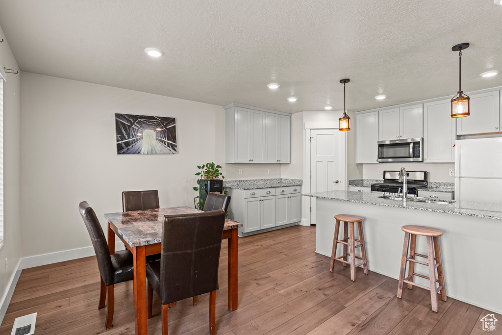Dining room with recessed lighting, wood finished floors, a textured ceiling, and baseboards