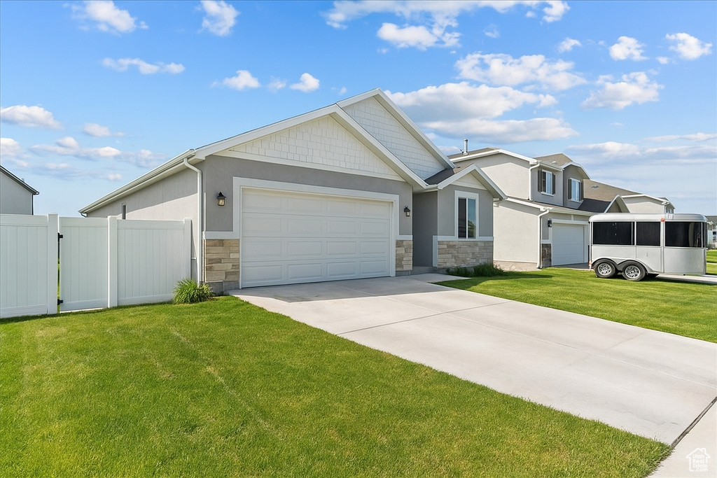 View of front of property featuring stone siding, driveway, an attached garage, and stucco siding
