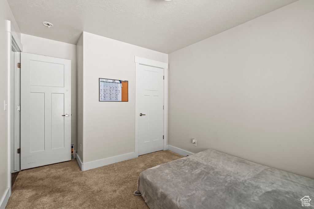 Carpeted bedroom featuring baseboards and a textured ceiling