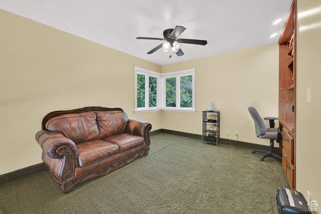 Carpeted office with a ceiling fan and baseboards
