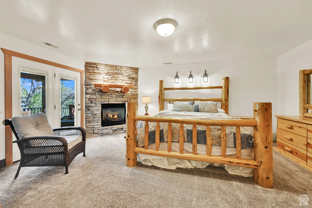 Carpeted bedroom with access to exterior and a stone fireplace