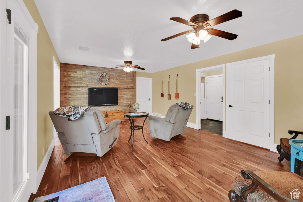 Living area with a ceiling fan, baseboards, and light wood-style flooring