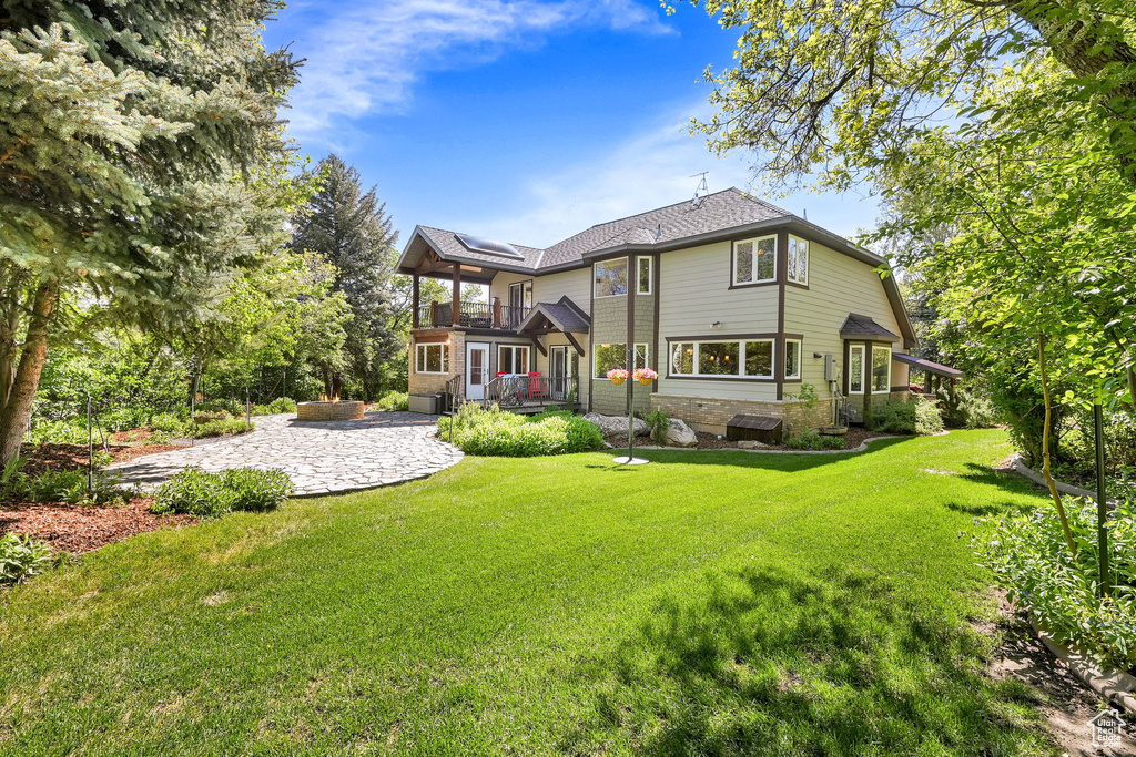Back of house with a balcony and a yard