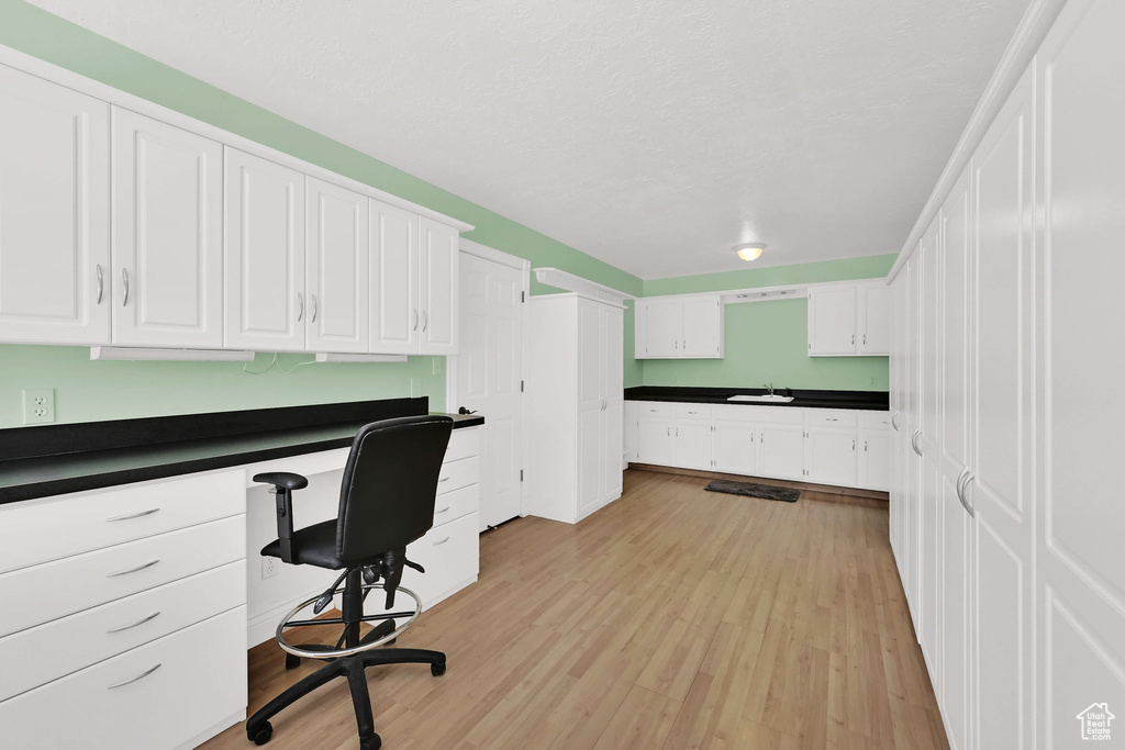 Office space with built in study area, a sink, and light wood-type flooring