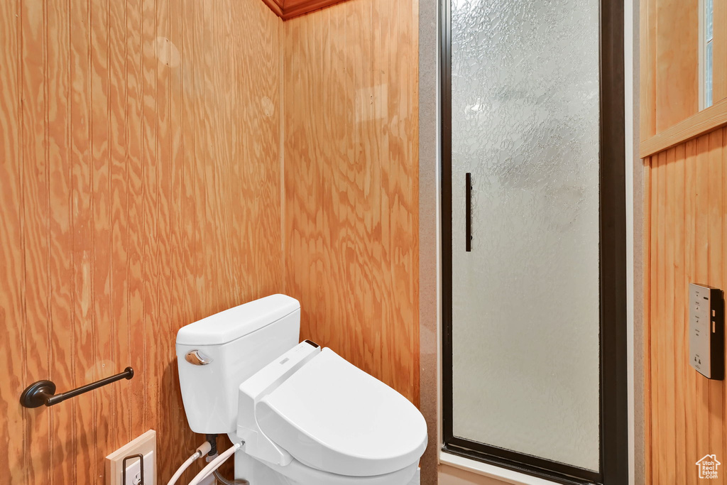 Bathroom with a stall shower, toilet, and wood walls