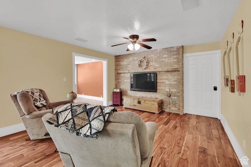 Living area with ceiling fan, baseboards, and light wood-style floors