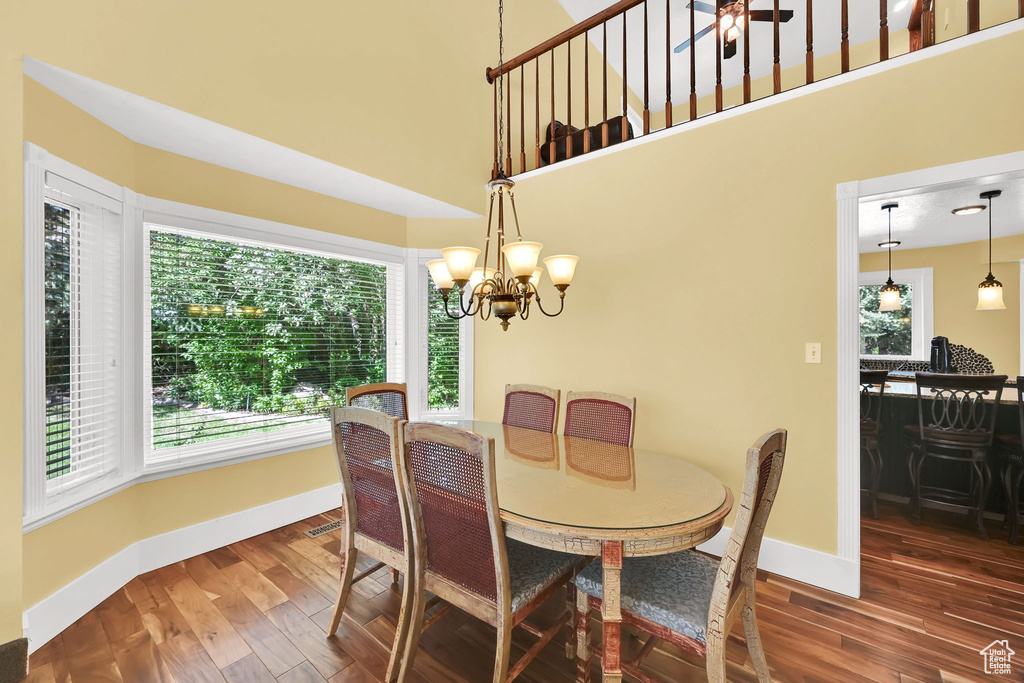 Dining area with a high ceiling, wood finished floors, baseboards, and a chandelier