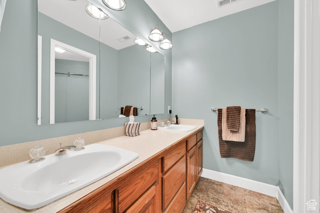 Full bath with baseboards and double vanity