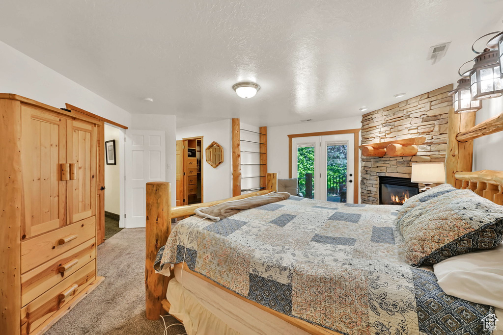 Bedroom with access to exterior, carpet, and a fireplace