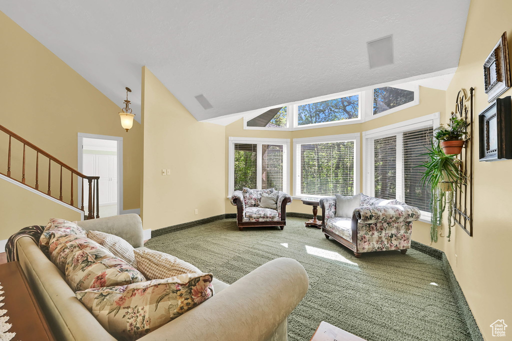 Carpeted living room featuring high vaulted ceiling, stairs, and baseboards