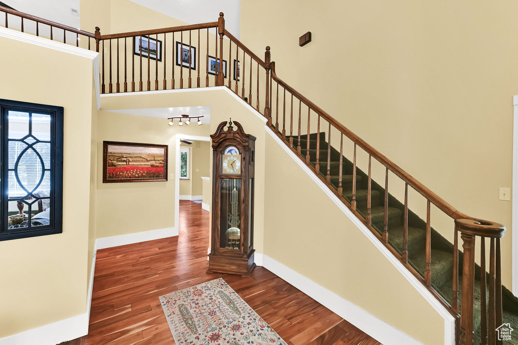 Stairs with wood finished floors, a towering ceiling, and baseboards